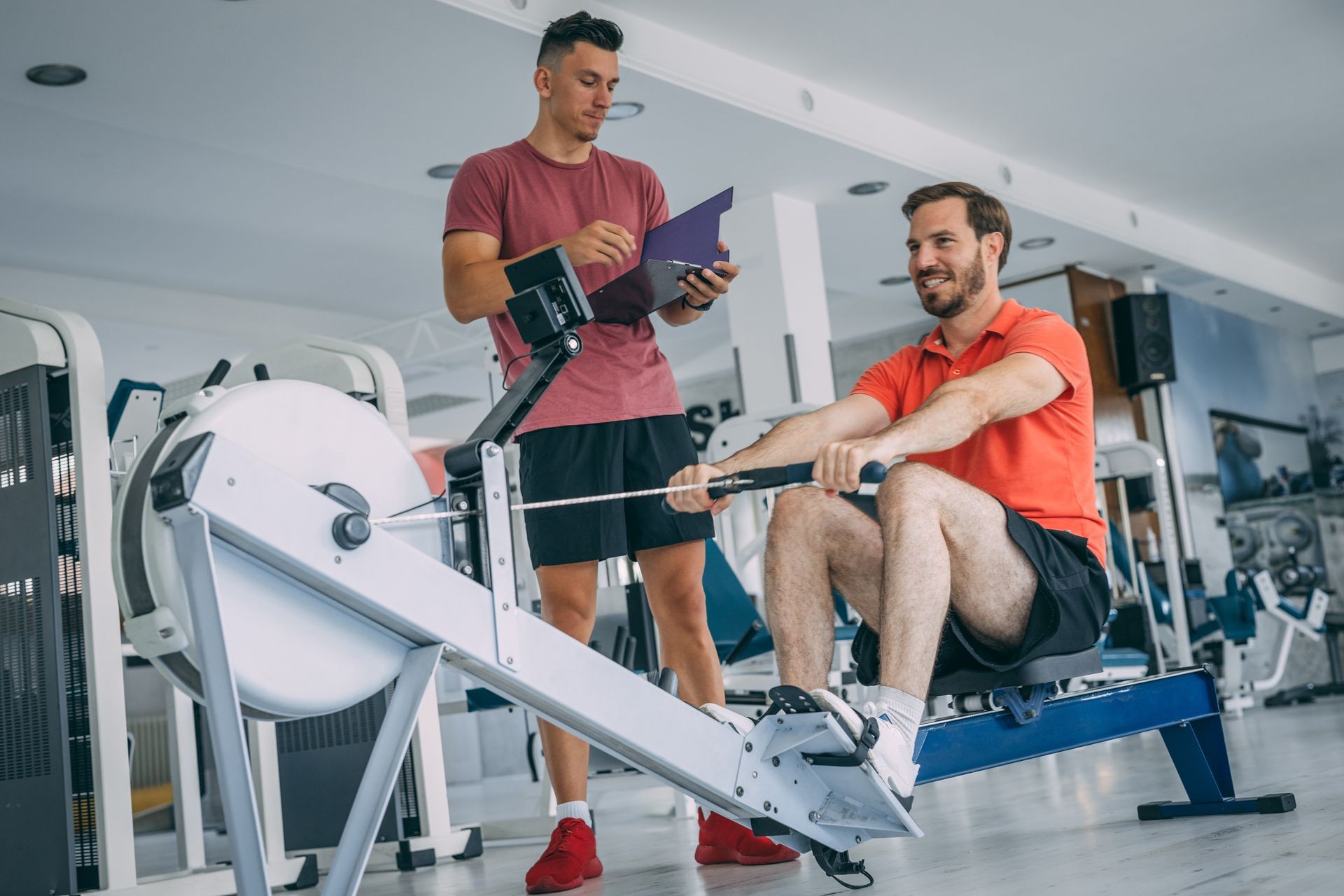 mid adult man using rowing machine at the gym.