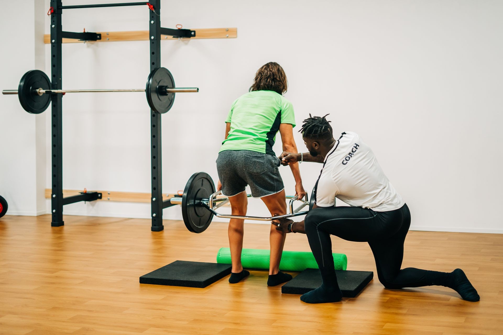 Black man coach training barbell with his patient in gym